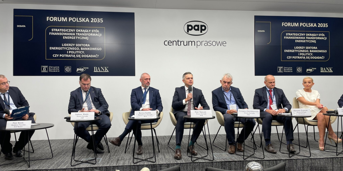 Pięciu mężczyzn siedzących na krzesłach podczas konferencji