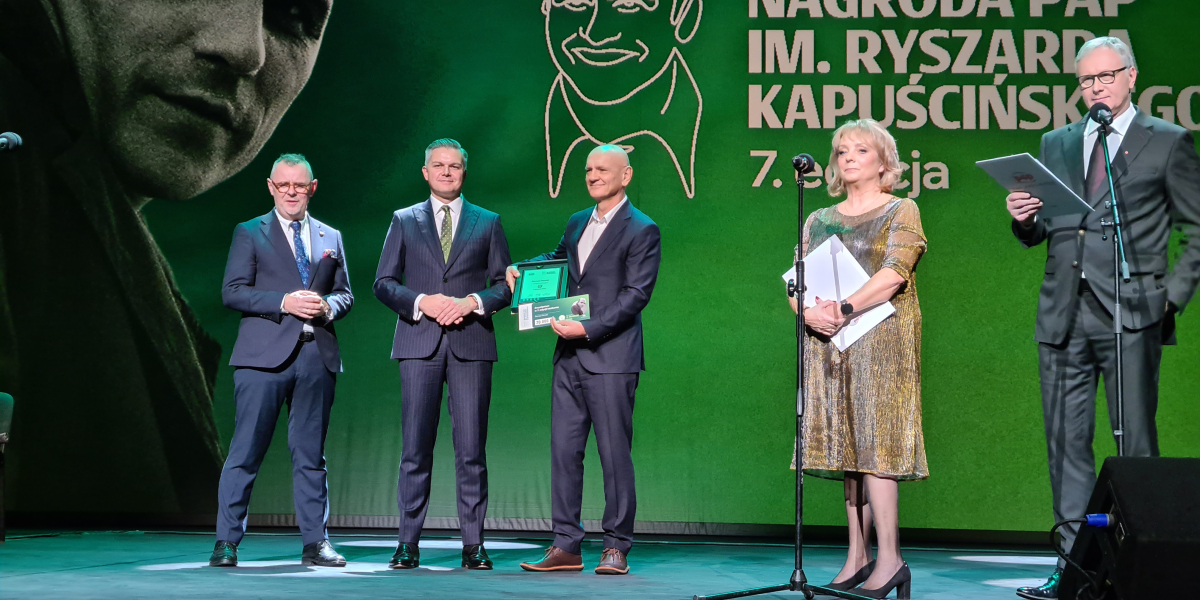 Ludzie na scenie pozujący do zdjęcia z nagrodą PAP im. Ryszarda Kapuścińskiego
