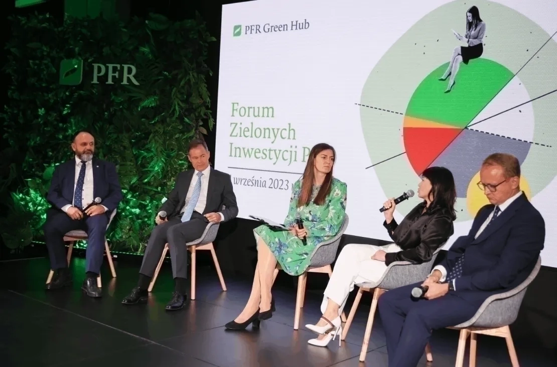 Grupa osób siedzących na scenie w półokręgu